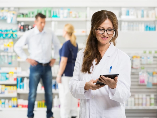 female pharmacist holding digital tablet at pharmacy